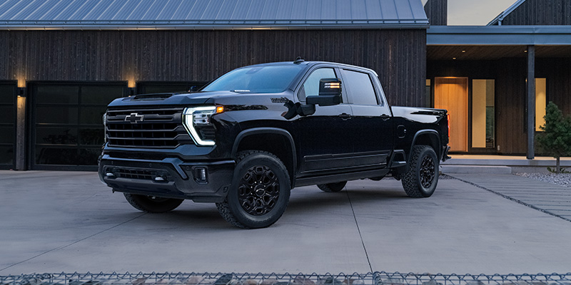 A black Chevrolet Silverado truck parked in front of a modern house.